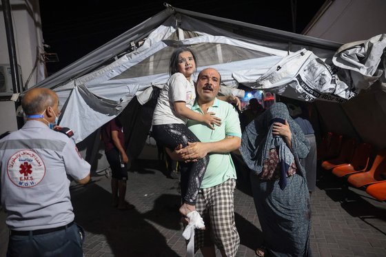 한 팔레스타인인 아버지가 6일 가자지구에 쏟아진 이스라엘군의 폭격으로 부상 당한 딸을 안고 병원으로 들어가고 있다. AFP=연합뉴스