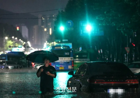 On the night of August 8, when a torrential downpour pounded Seoul, a citizen wades through the water after the roads near Daechi Station in Seoul were flooded. Seong Dong-hun