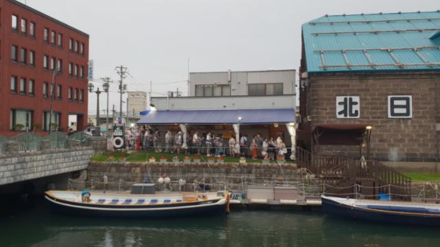 오타루 운하에서 나룻배를 타기 위해 기다리는 관광객들. 비가 와 우비를 입고 줄을 섰다. 양승준 기자