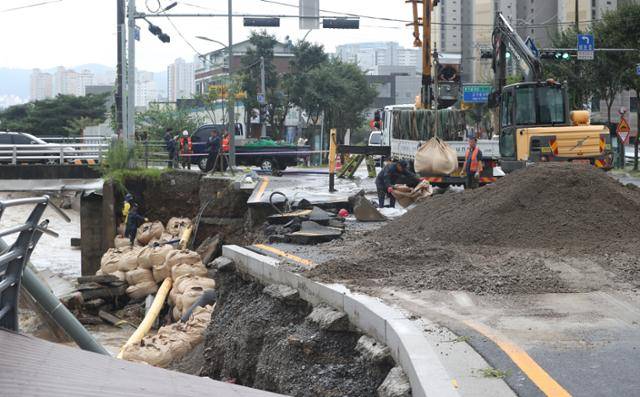 9일 오후 경기 용인시 수지구 동천동 동막천이 범람하면서 도로가 침하되고 도로변에 조성된 덱(deck) 길이 무너져 내려 관계자들이 복구작업을 하고 있다. 뉴스1