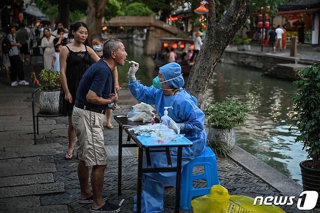31일(현지시간) 중국 상하이 주가각 고대 물마을의 수로 옆에서 한 보건원이 한 남자를 코로나19 검사하고 있다. ⓒ AFP=뉴스1 ⓒ News1 박기현 기자