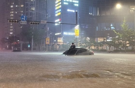 지난 8일 서울 서초동에서 침수된 차량 위로 올라가 몸을 피하고 있는 한 남성의 모습. 누리꾼들은 해탈한 듯 물이 빠지기를 기다리는 그에게 '서초동 현자'라는 별명을 붙였다. 온라인 커뮤니티 캡처