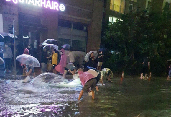 - 10일 폭우가 내린 충북 청주시 흥덕구 복대동의 한 아파트 주민들이 지하주차장 침수를 막기 위해 직접 나서 빗물을 퍼내고 있다. 트위터 캡쳐