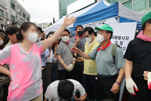 11일 수해 복구 자원봉사를 위해 오전 서울 동작구 사당동을 찾은 국민의힘 주호영 비상대책위원장과 권성동 원내대표, 나경원 전 의원 등에게 한 시민이 길을 터 줄 것을 요구하고 있다. / 연합뉴스