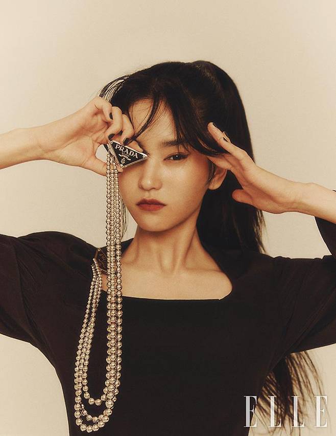 쇄골을 유니크하게 드러내는 블랙 드레스와 자유자재로 레이어드할 수 있는 로고 장식의 실버 브로치는 모두 Prada.