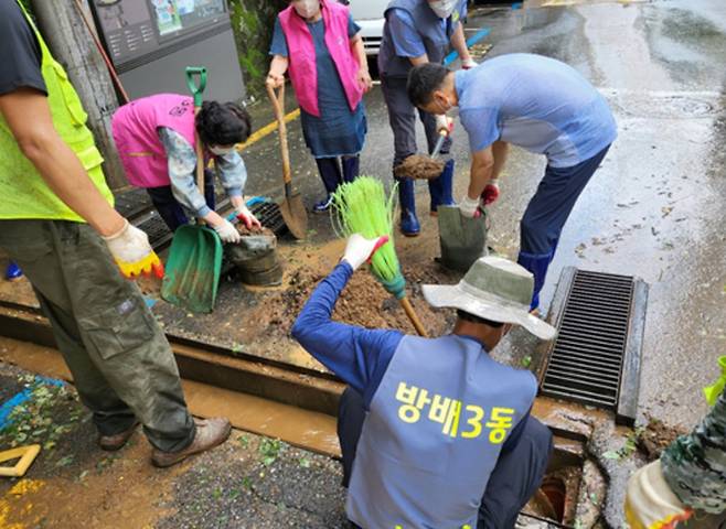 서울 서초구 민관 응급복구단이 방배3동 침수 지역의 빗물받이 토사제거 작업을 함께 하고 있다. |서초구 제공