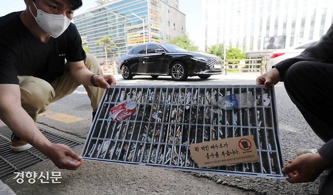 이제석광고연구소 직원과 활동가들이 12일 서울 강남구청 앞에서 ‘꽉 막힌 배수구가 홍수를 부릅니다’ 캠페인을 하며 꽉 막힌 배수구 사진 스티커를 도로에 붙이고 있다. 김창길 기자