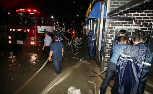 10일 충북 청주시 흥덕구 복대동에서 시민들과 소방당국이 도로에 찬 물을 빼내고 있다. 연합뉴스