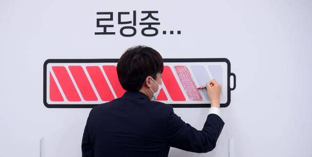 이준석 대표가 지난해 7월 26일 최고위원회의실 배경에 '인재 영입'의 진행상황을 표시하는 의미로 그려진 '로딩중...'의 빈칸에 빨간색 칠을 하고 있다. 오대근 기자