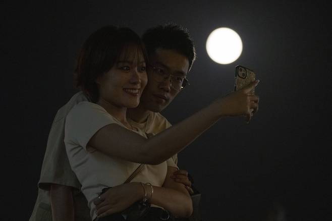 11일(현지시간) 중국 베이징 시내 하늘에 뜬 슈퍼문을 배경으로 시민들이 셀카를 촬영하고 있다. [AP=연합뉴스]