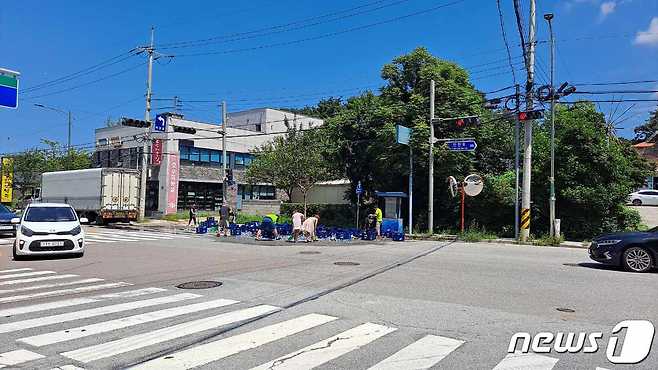 지난 12일 11시 30분쯤 춘천 만천리의 한 도로에서 좌회전하던 주류 트럭의 윙바디(날개 형태 문)에서 갑자기 맥주 박스 수십 개가 쏟아진 가운데 시민들이 자발적으로 도로를 정리하고 있다.(독자 제공)