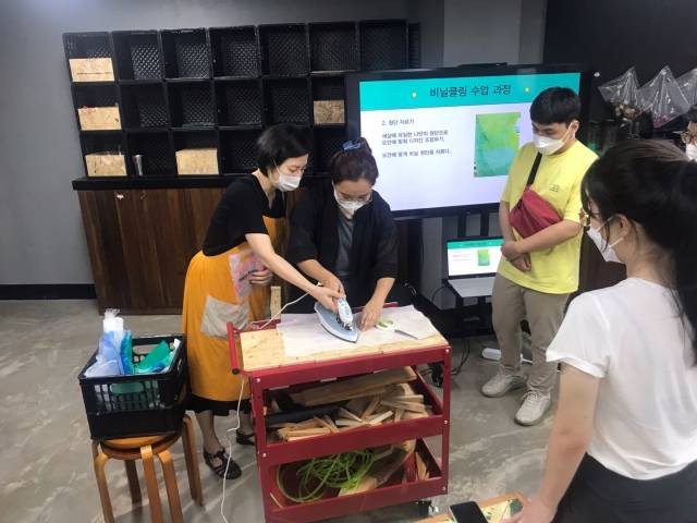 '비닐클링' 수업에서 한 청년이 비닐을 다림질하고 있다. 겹겹이 쌓은 비닐을 자르고 쌓아, 바느질로 고정 시키면 카드지갑이 된다.