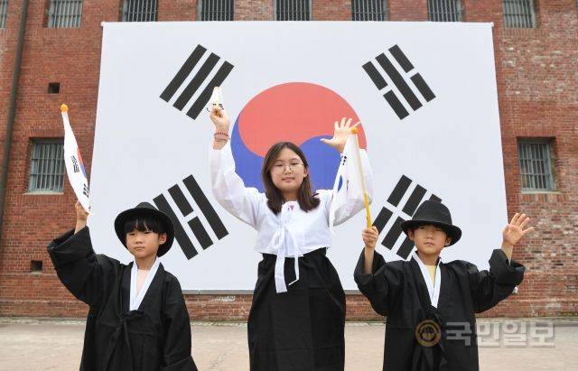 광복절 77주년을 하루 앞둔 14일 시민들이 서울 서대문형무소역사관 앞 대형 태극기 앞에서 기념촬영을 하고 있다.