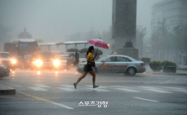 중부 지역을 중심으로 집중호우가 내린 15일 한 여성이 서울 세종로 사거리에서 서둘러 발걸음을 옮기고 있다. 사진|강윤중 기자