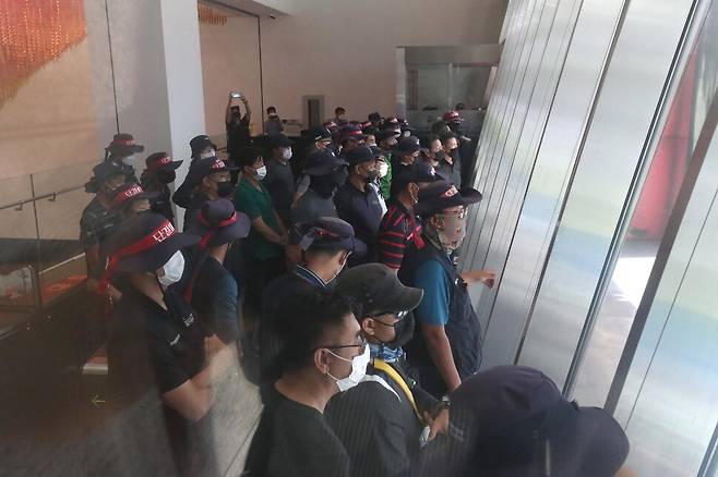 공공운수노조 화물연대본부 하이트진로지부 조합원들이 16일 서울 강남구 청담동 하이트진로 본사 사옥 옥상 광고판과 1층 로비를 점거하고 농성을 벌이던 중, 사옥 들머리에서 열리는 화물연대본부의 기자회견을 지켜보고 있다. 강창광 선임기자