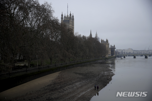 [런던=AP/뉴시스] 영국이 47년 만에 유럽연합과 완전히 결별한 1일 아침 물이 바다로 빠져나간 템즈강 물가를 두 사람이 걸어가고 있다. 뒤에 영국 의사당 건물이 보인다. 2021. 1. 1.