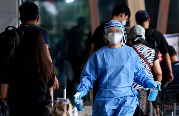 소독약 뿌리는 관계자 - 광복절인 15일 오전 서울 송파구보건소에 마련된 코로나19 임시선별진료소에서 관계자가 검사를 기다리는 시민들이 지나간 자리에 소독약을 뿌리고 있다.      중앙방역대책본부에 따르면 이날 0시 기준 신규확진자수는 6만2078명으로 집계됐다. 하지만 위중증 환자수는 521명으로, 4월29일(526명) 이후 108일만에 최다치를 기록했다. 2022.8.15 연합뉴스