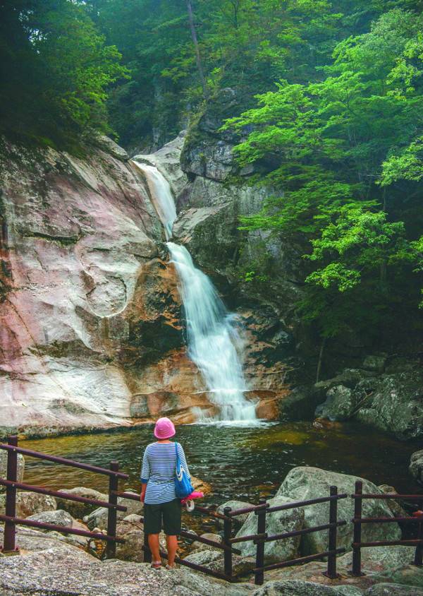 소금강 제1경에 꼽히는 구룡폭포를 찾은 탐방객이 거대한 바위를 타고 용틀임하듯 쏟아지는 물줄기를 바라보고 있다.