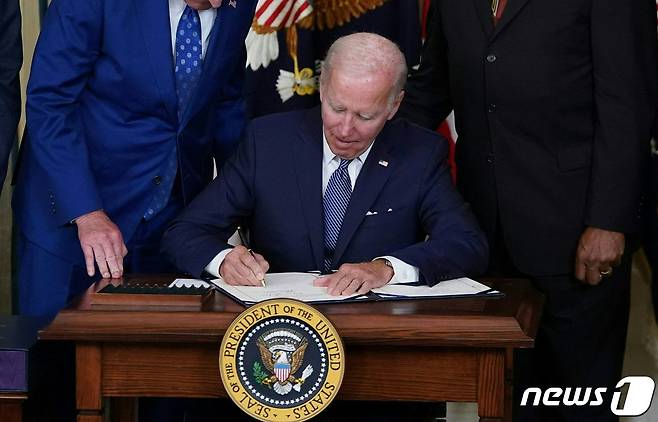 조 바이든 미국 대통령이 16일 (현지시간) 워싱턴 백악관에서 기후변화 대응과 의료보장 확충, 대기업 증세 등을 담은 '인플레이션 감축법'에 서명을 하고 있다. ⓒ AFP=뉴스1