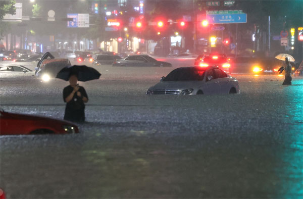 지난 8일 밤 서울 강남구 대치역 인근 도로가 물에 잠기면서 침수된 차량을 버리고 운전자들이 대피하고 있다. [사진 출처 = 연합뉴스]