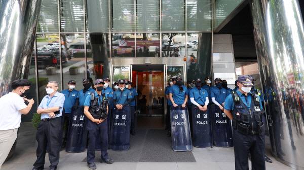 전국민주노동조합총연맹(민주노총) 공공운수노조 화물연대가 서울 강남구 하이트진로 본사 점거 농성에 돌입한 지난 16일 오전 경찰 관계자 등이 입구에 서 있다. [사진 출처 = 연합뉴스]