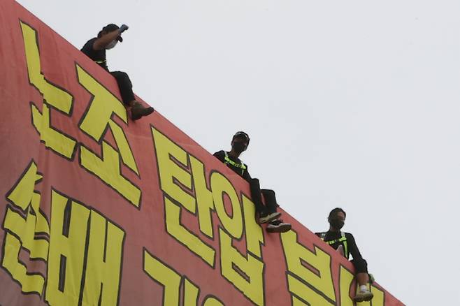 하이트진로에서 고공농성을 펼치고 있는 화물노동자들이 18일 서울 강남구 하이트진로 본사 앞에서 열린 화물연대 고공농성투쟁 승리 결의대회 참가자들의 격려에 호응하고 있다. 연합뉴스