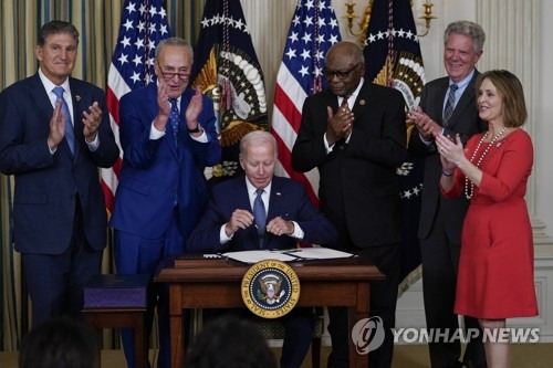 조 바이든(가운데) 미국 대통령이 16일(현지시간) 백악관에서 기후변화 대응과 의료보장 확충 등의 내용이 담긴 '인플레이션 감축법'에 서명하고 있다./연합뉴스