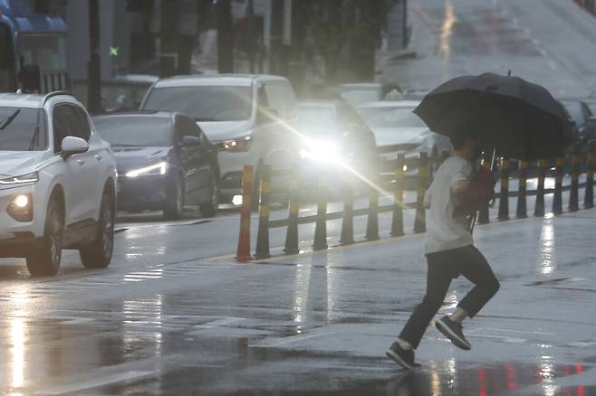 19일 오후 서울 마포구의 한 횡단보도에서 전조등을 켠 차량들 앞으로 우산을 쓴 시민이 달려가고 있다. 이정아 기자 leej@hani.co.kr