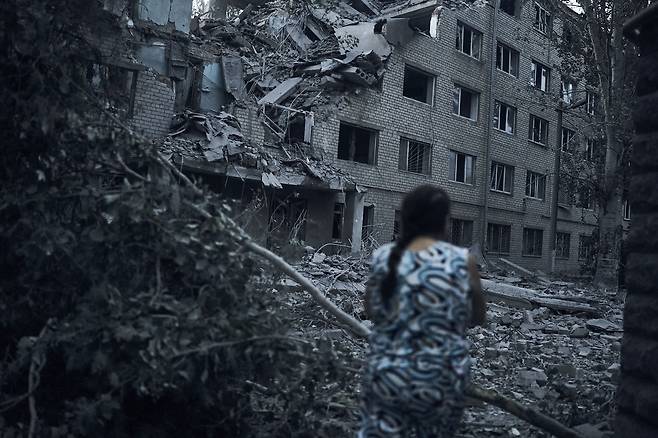 한 우크라이나 여성이 지난 2일(현지 시각) 우크라이나 미콜라이우에서 야간 포격을 받아 파괴된 건물 옆을 지나고 있다. /연합뉴스