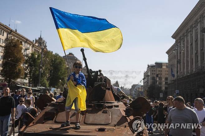 파괴된 러시아 장갑차량에서 국기 흔드는 우크라이나 어린이 (키이우 로이터=연합뉴스) 21일(현지시간) 우크라이나군이 노획해 수도 키이우 광장에 전시한 러시아 장갑차량 위에서 우크라이나 어린이가 국기를 흔들고 있다. 우크라이나는 24일 독립기념일을 앞두고 파괴하거나 노획한 러시아 무기들을 대중에 공개했다. 2022.8.21 photo@yna.co.kr