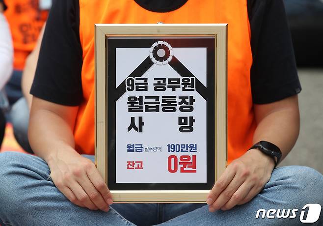 전국공무원노동조합(이하 전공노) 회원들이 지난 10일 오후 서울 용산구 대통령실 인근에서 가진 '임금인상 쟁취 및 인력감축 저지 총력투쟁 결의대회'에서 '9급 공무원 월급통장 사망' 문구를 들고 있다. 2022.8.10/뉴스1 ⓒ News1 송원영 기자