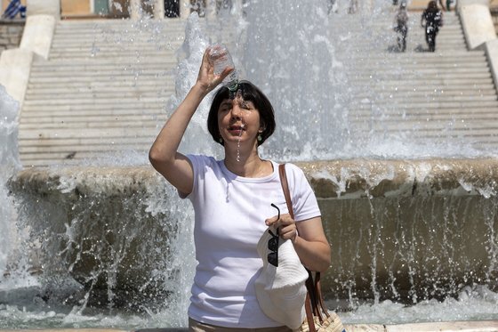 지난 6월 22일 폭염이 뒤덮은 그리스 아테네에서 한 여성이 머리에 물을 붓고 있다. 신화=연합뉴스