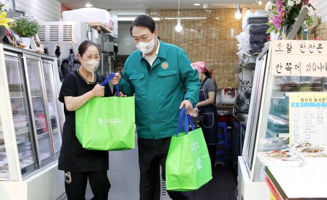 윤석열 대통령이 25일 오전 서울 강동구 암사종합시장을 방문, 한 반찬가게 직원으로부터 온라인으로 주문된 상품을 받아들고 있다. 연합뉴스