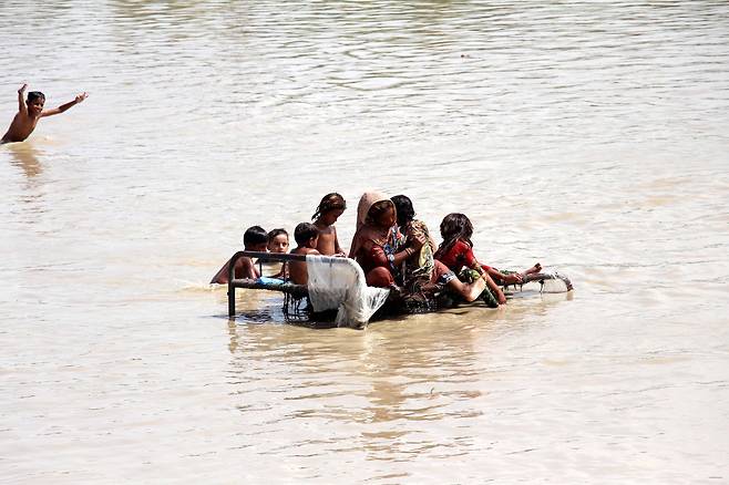 28일(현지시간) 파키스탄 신드 주(州) 지역에서 어린이들이 물 위에 떠 있는 부서진 침대 위에 올라가 있다. EPA=연합뉴스
