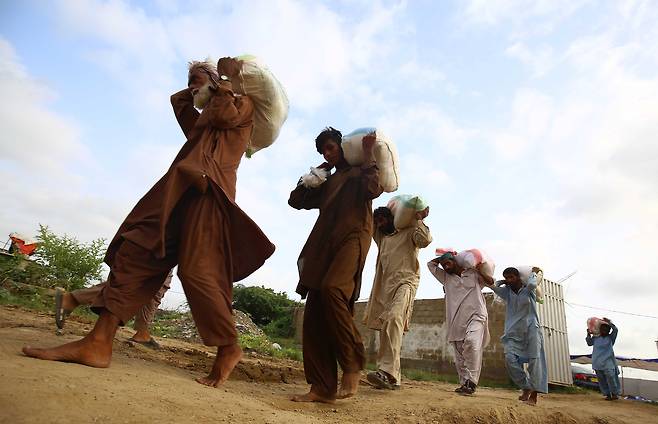 28일 파키스탄 카라치 지역 이재민들이 구호품을 옮기고 있다. EPA=연합뉴스