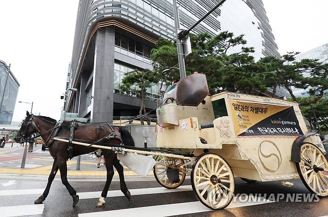 판교역에 마차 보낸 '우마무스메' 게이머들 (성남=연합뉴스) 홍기원 기자 = 카카오게임즈의 '우마무스메:프리티 더비' 국내 이용자들이 게임사 측의 운영 방침에 반발하는 항의 문구 현수막을 붙인 마차가 29일 오전 카카오게임즈 본사가 위치한 경기도 성남시 판교역 인근 도로를 달리고 있다. 2022.8.29 xanadu@yna.co.kr