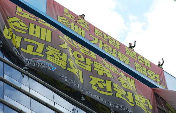 지난 24일 서울 강남구 하이트진로 본사에서 옥상 농성을 이어가고 있는 화물연대 조합원들이 구호를 외치고 있다. [연합뉴스]