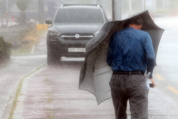 태풍 힌남노가 한반도를 향해 북상 중인 5일 오전 제주도 성산읍에서 한 시민이 우산을 쓰고 가고 있다. 연합뉴스