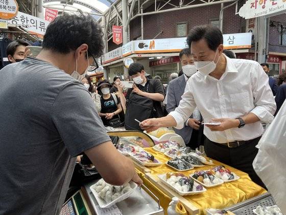 8일 자양전통시장을 방문한 오세훈 서울시장이 떡을 사고 돈을 내고 있다. 문희철 기자