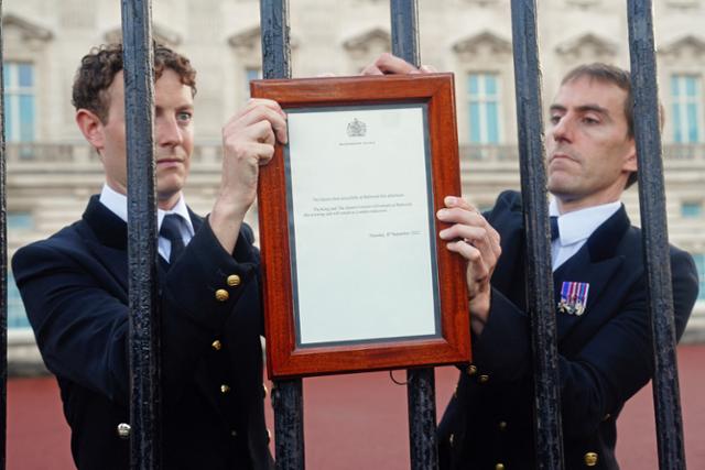 8일 영국 왕실 직원들이 런던 버킹엄궁 철책에 엘리자베스 2세 여왕 서거를 알리는 안내문을 걸고 있다. 런던=AFP 연합뉴스