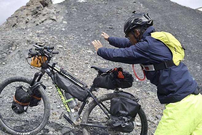박종하 씨가 끌고 올라온 자전거를 산 정상에서 던지고 있다. 자전거를 왜 던졌냐는 질문에 그는 ″너무 힘들어서 그랬다. 대회 나가보면 이해할 수 있게 된다″고 답했다. 사진 SRMR
