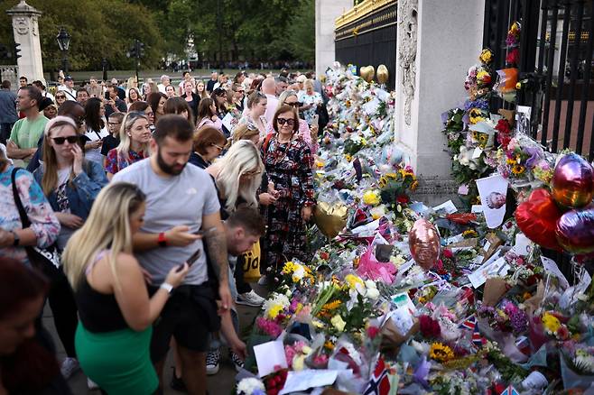 People view and place floral tributes at the gates of Buckingham Palace, following the death of Britain's Queen Elizabeth II, in London, Sunday. (Reuters-Yonhap)