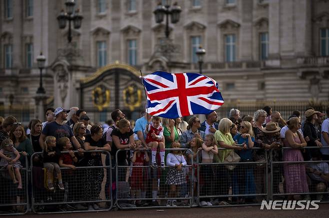 [런던=AP/뉴시스] 11일(현지시간) 영국 런던의 버킹엄 궁전 앞에서 엘리자베스 2세 여왕을 애도하며 헌화를 마친 시민들이 모여 있다. 2022.09.12.