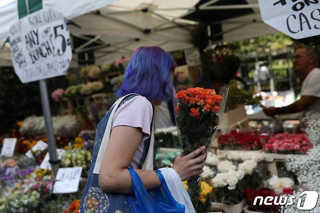 영국 런던의 컬럼비아 로드 꽃시장에서 11일(현지시간) 한 시민이 고(故) 엘리자베스 2세 여왕을 추모하기 위해 꽃다발을 구매하고 있다. ⓒ AFP=뉴스1 ⓒ News1 김예슬 기자