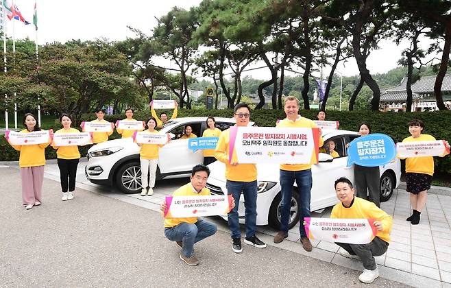 오비맥주 임직원들이 지난 14일 강남구 삼성동 본사 앞에서 음주운전방지장치 설치 후 기념 사진을 찍고 있다. 맨 앞줄 왼쪽부터 구자범 오비맥주 법무정책홍보 부사장, 배하준 오비맥주 대표. /오비맥주 제공