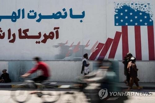 탈레반이 카불에서 미국 국기를 조롱하는 내용의 벽화 앞을 지나는 모습 [AFP 연합뉴스 자료사진. 재판매 및 DB 금지]
