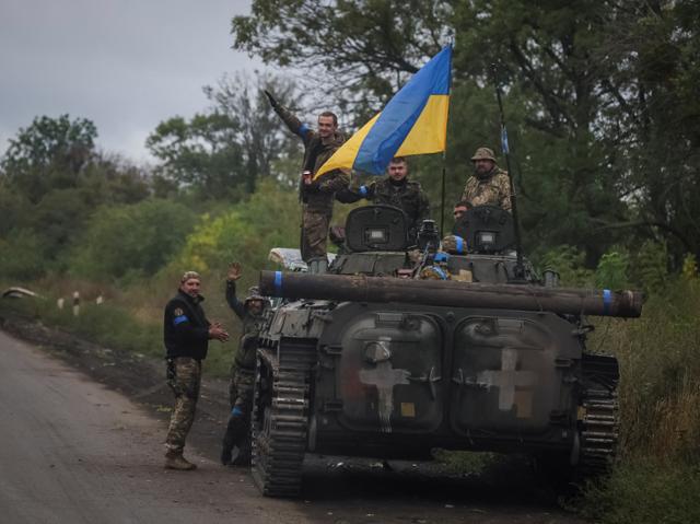우크라이나 병사들이 14일 러시아에 점령됐다가 최근 수복한 동북부 하르키우주 이지움 인근에서 우크라이나 국기를 꽂은 BMP-2 보병 전투 차량 위에 선 채 손을 흔들고 있다. 이지움=로이터 연합뉴스