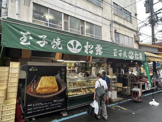 지난 1일 오전 11시 츠키시 시장에 있는 계란말이 전문점 쇼로 앞. 여느 시장처럼 상인들은 지나가는 손님들에게 '어서 오세요'라고 반갑게 인사를 한다. 쇼로 가게 앞에서 손님들이 계란말이를 사고 있다. 사진 김현예 특파원