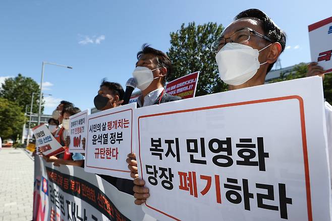 19일 서울 용산구 대통령 집무실 인근에서 열린 윤석열 정부 복지 민영화 선언 규탄 기자회견에서 한 참가자가 복지 민영화 폐기를 주장하는 팻말을 들고 있다. 연합뉴스