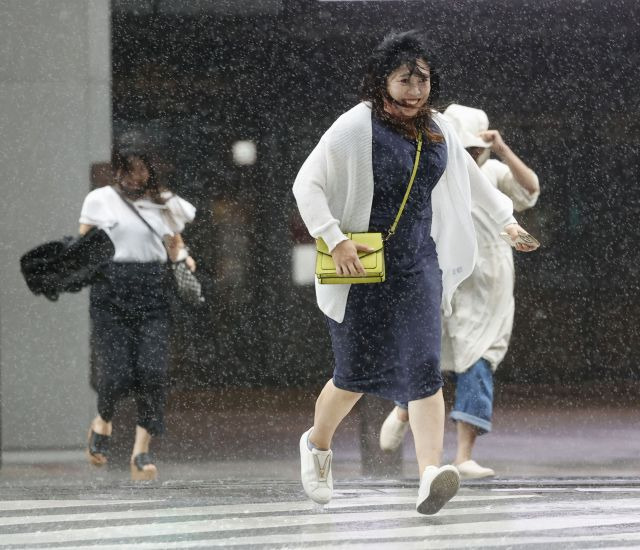 日本九州西南部鹿島市民たちが去る 18日第14号台風 ‘乱麻石’で零れ落ちる雨降りを傘なしにくぐって横断歩道を渡っている. AP連合ニュース